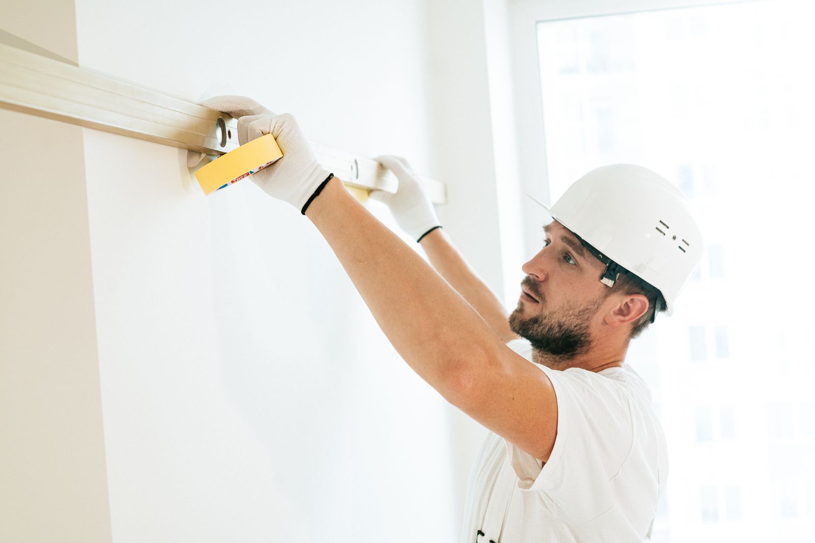Tradesperson using a spirit level on an interior wall — automation that runs the repeatable parts of the operation so the team focuses on the work