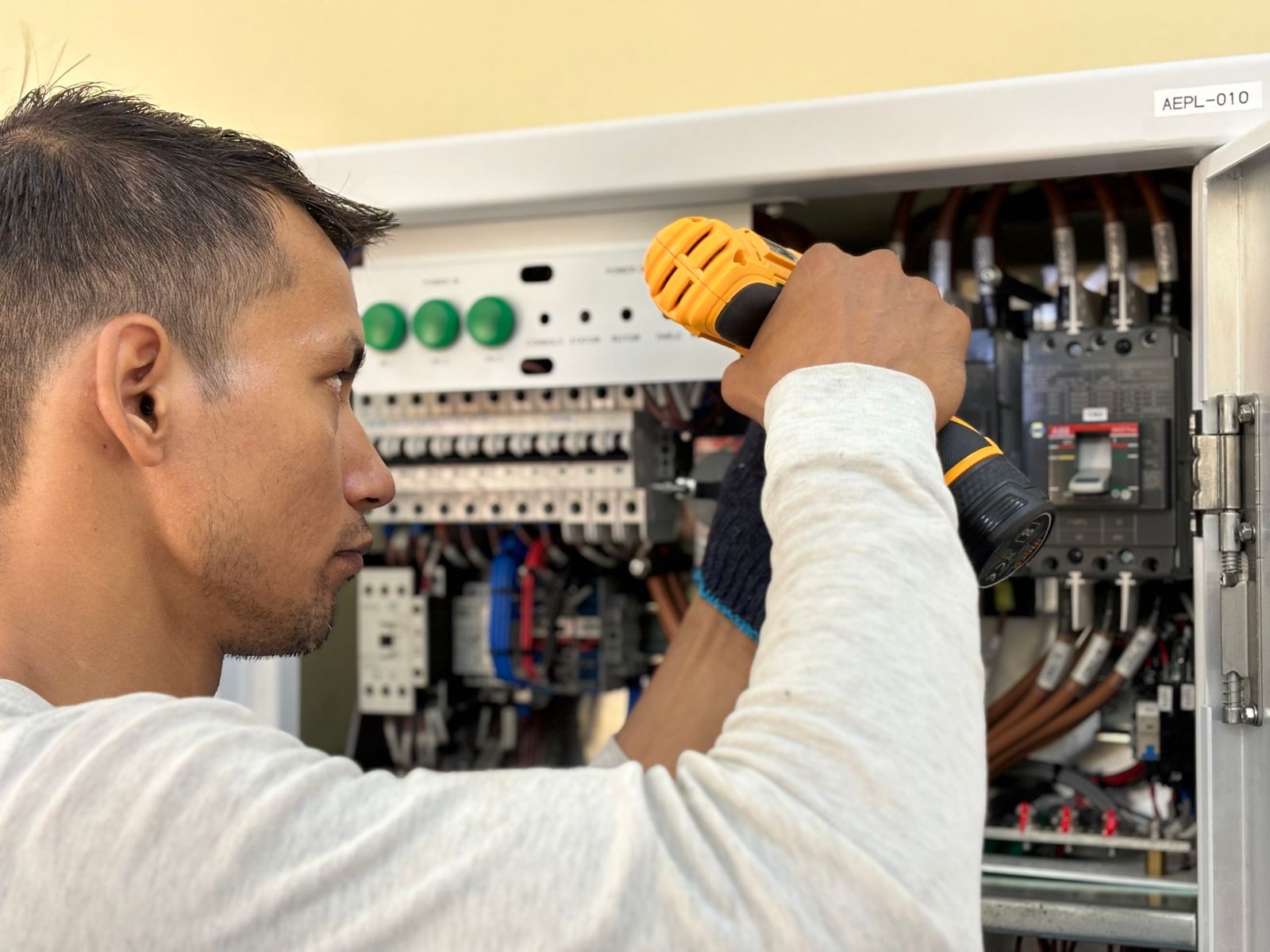 Electrician drilling into a circuit breaker panel — the work happens fast; the invoice usually does not