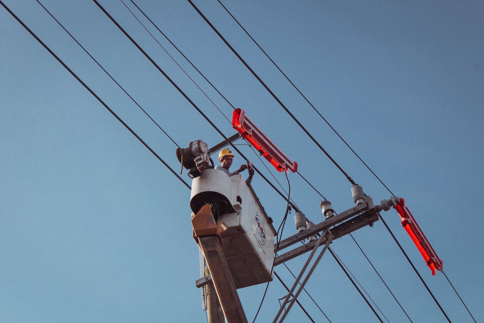 Electrician in a cherry picker working on overhead power lines — the specialised electrical work that often needs a custom-built tool
