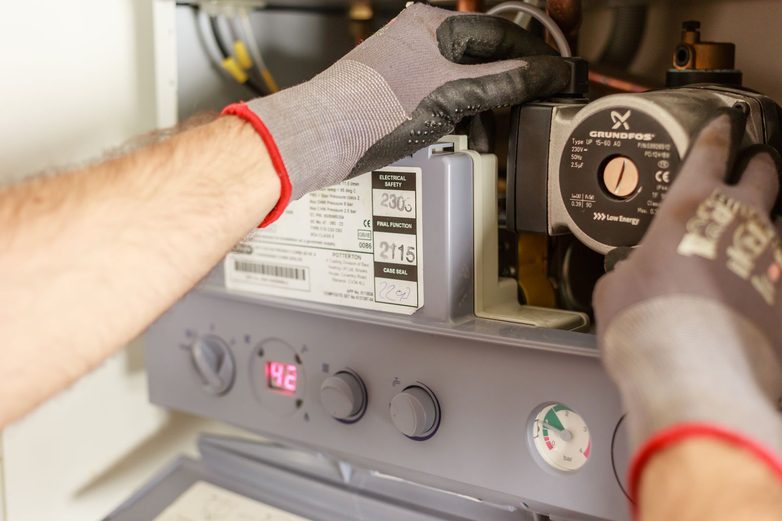 Gasfitter's hands adjusting a boiler system with precision instruments — the kind of job that cannot be invoiced until the GCC is lodged