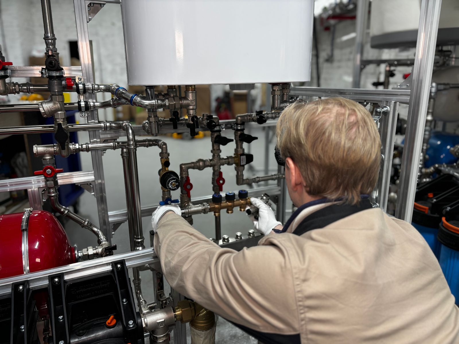 Plumber adjusting industrial pipework — the kind of commercial RPZ valve work that drives an annual testing program