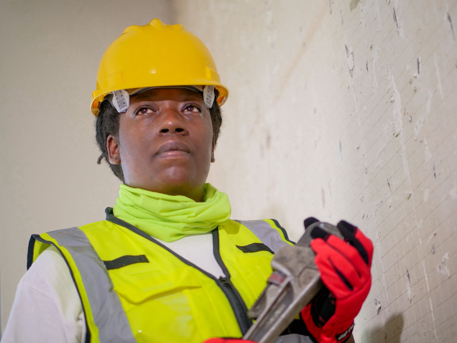 Tradesperson in safety gear holding a wrench — emergency call-out work where dispatch coordination breaks down fast