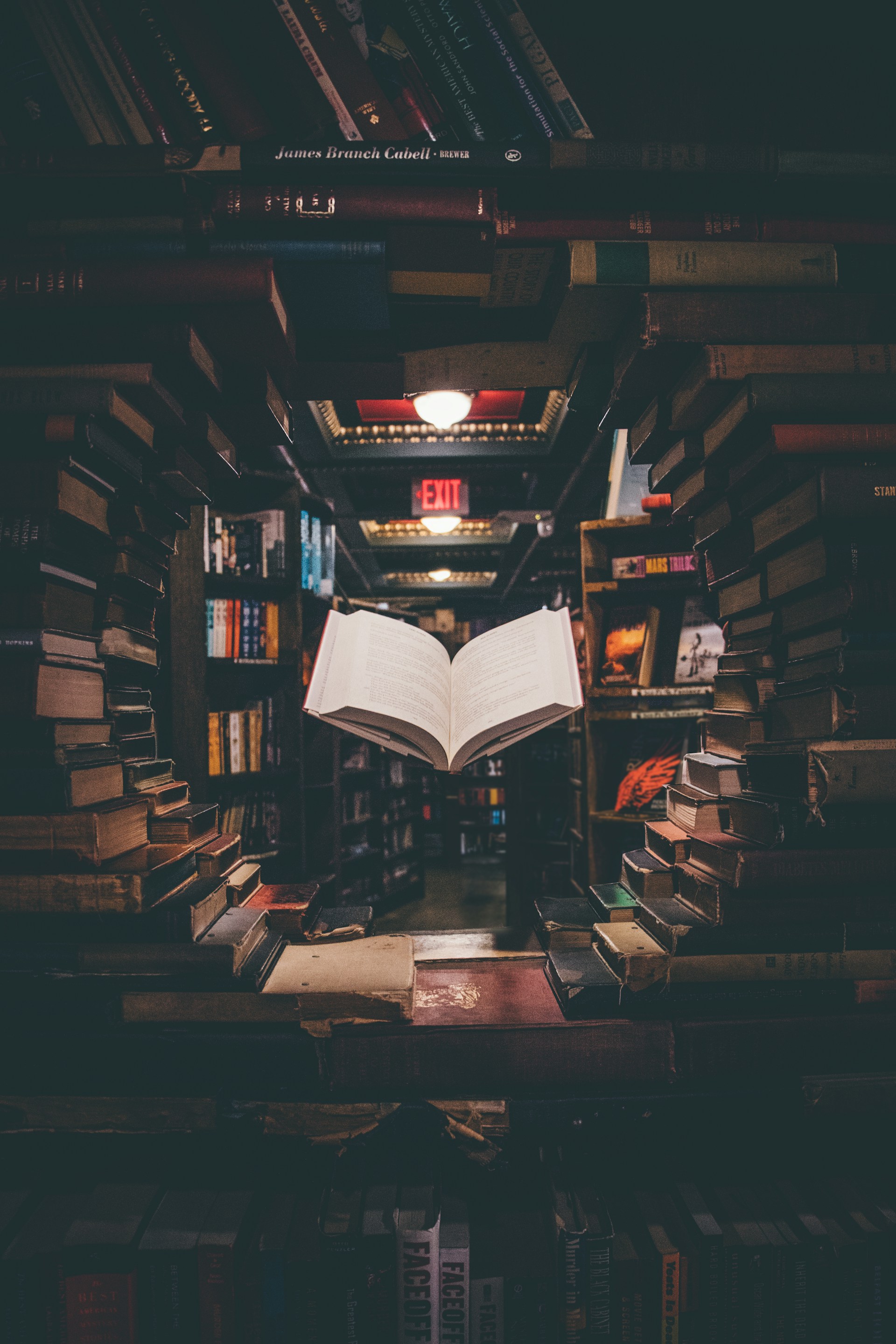 Open book floating in a dark library surrounded by stacks of books, representing private knowledge as an asset